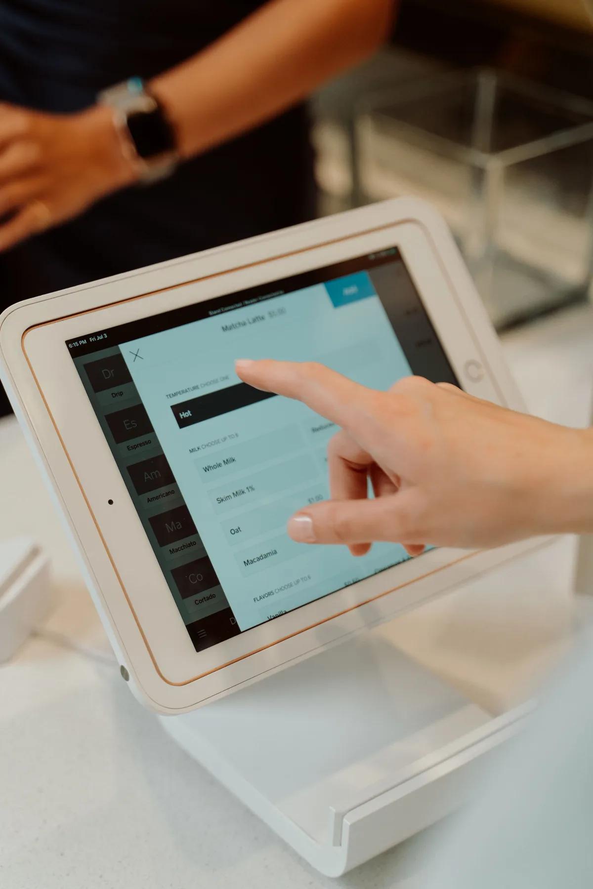 A customer tapping an order form on a counter tablet.
